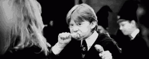 a black and white photo of a boy eating a piece of food from a woman 's hand .