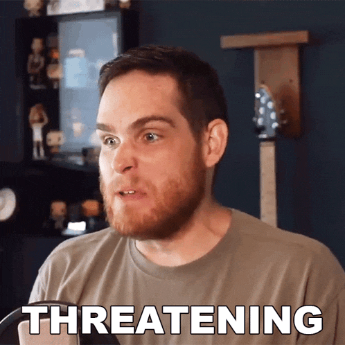 a man with a beard has the word threatening written on his shirt