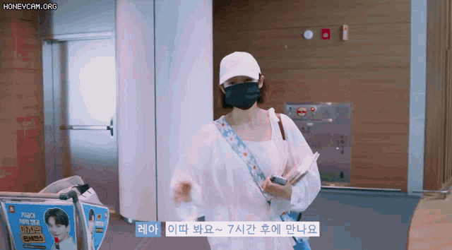 a woman wearing a mask and a white hat is standing in a hallway