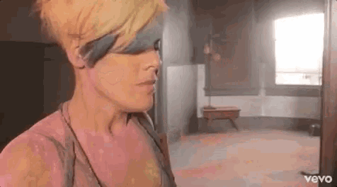 a woman with short blonde hair is standing in a room with a window .