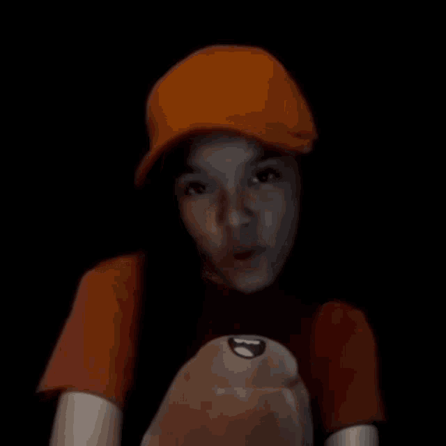 a young boy wearing an orange hat and a red shirt is making a funny face .