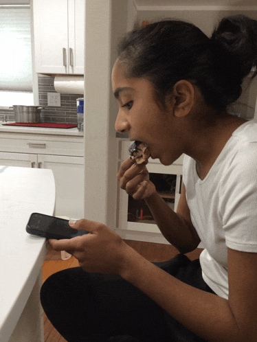 a woman eating while looking at her phone
