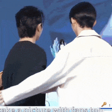 two men are hugging each other in front of a microphone with the words take a picture with fans too .
