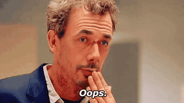 a man with a beard and mustache is holding his hand to his mouth and saying oops .