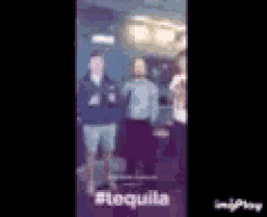 a group of people are standing next to each other in a room with the word tequila on the bottom .