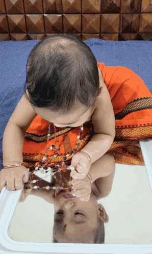 a baby is playing with a mirror and looking at its reflection