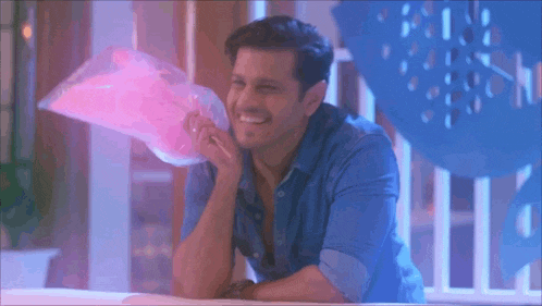 a man in a blue shirt is holding a bag of pink powder