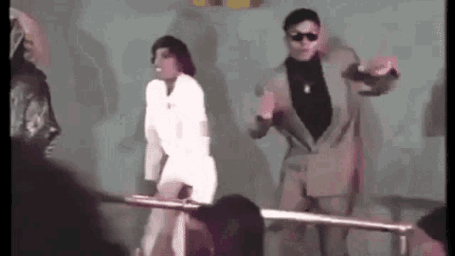 a man in a suit is dancing with a woman in a white dress .
