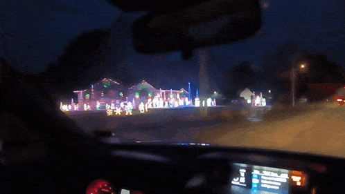 a car is driving down a road at night with a lot of christmas lights
