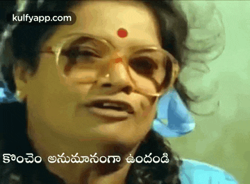 a woman with glasses and a red dot on her forehead is talking in a foreign language .
