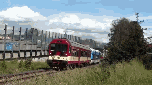 a red and white train is going down the tracks near a fence