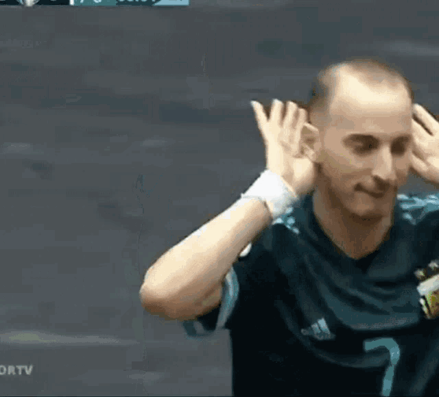 a man wearing a shirt with the number 7 on it covering his ears