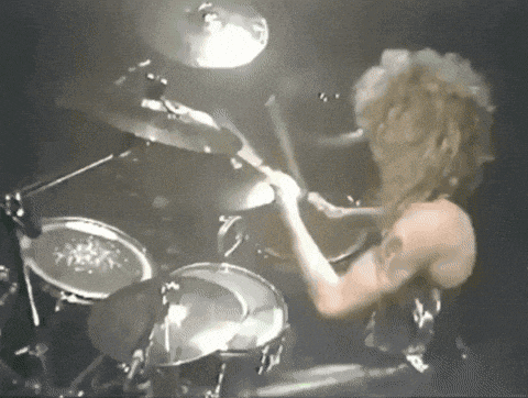 a man is playing a drum set in the dark
