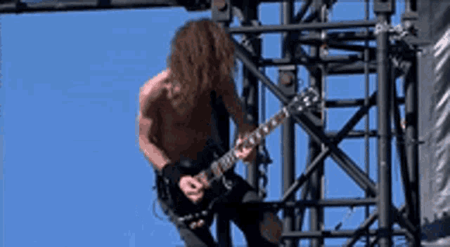 a shirtless man is playing a guitar on stage