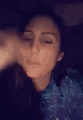 a woman with her eyes closed is wearing a blue shirt .