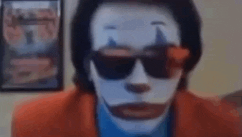 a close up of a person wearing a clown costume and makeup .