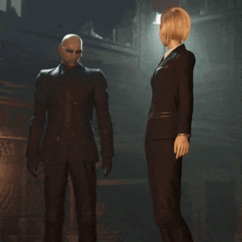 a man in a suit stands next to a woman in a black suit