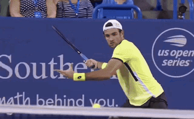 a man is playing tennis in front of a sign that says " us open series "