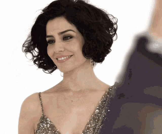 a woman in a sequined dress is smiling and looking to the side