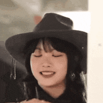 a woman wearing a black hat and headphones is smiling with her eyes closed .