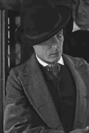 a black and white photo of a man wearing a hat .
