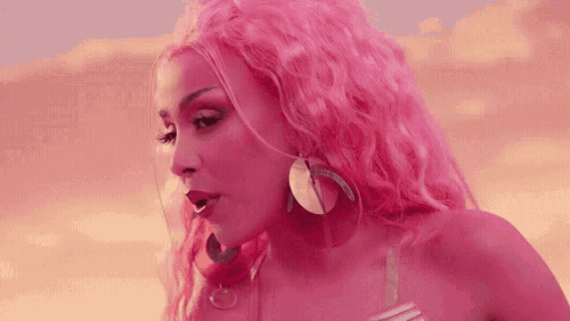 a woman with pink hair and earrings is wearing a pink bikini .