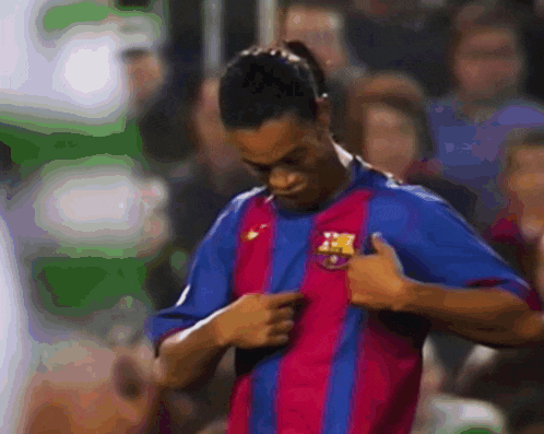 a soccer player in a striped shirt with a fcb logo on his chest giving a thumbs up