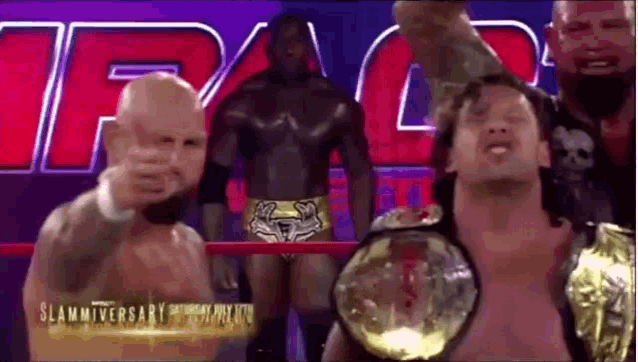 a group of wrestlers are standing in a ring and one of them is wearing a championship belt .