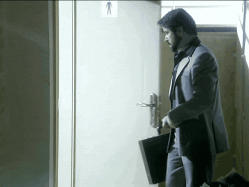 a man in a suit holds a briefcase while standing in front of a door with an arrow pointing up