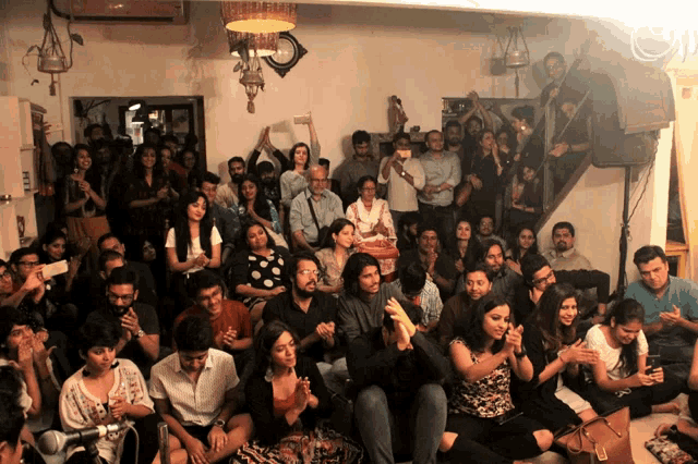 a large group of people are gathered in a room with a clock on the wall that says ' a '