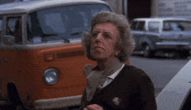 a woman is standing in front of an orange vw van