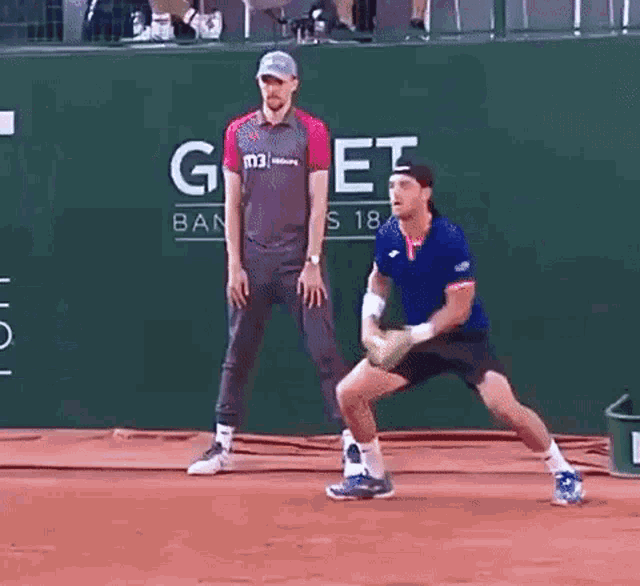 a man holding a tennis racquet on a tennis court in front of a gone banner