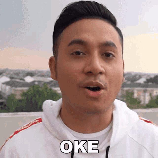 a man wearing a white hoodie with the word oke on his chest