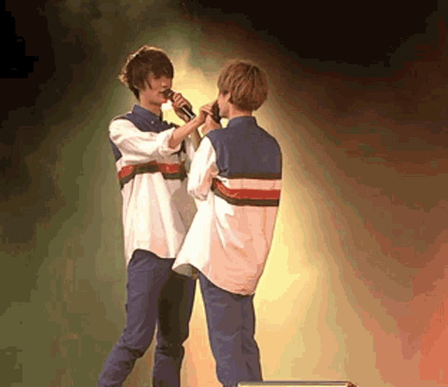 a man singing into a microphone next to another man