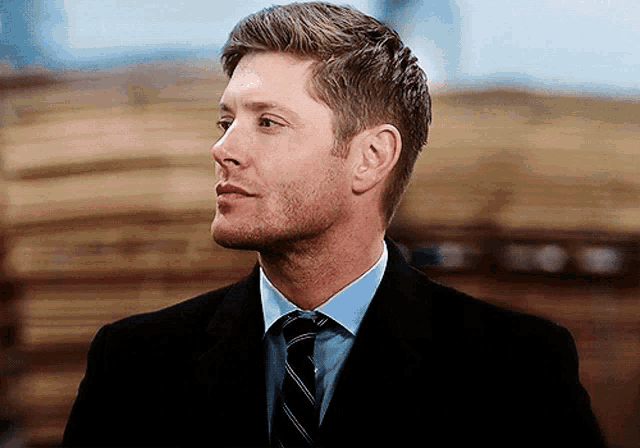 a man wearing a suit and tie looks to his left