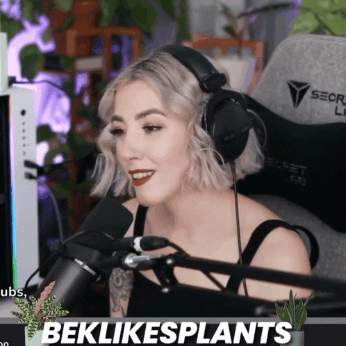 a woman is wearing headphones and smiling in front of a microphone with the words beklikesplants behind her