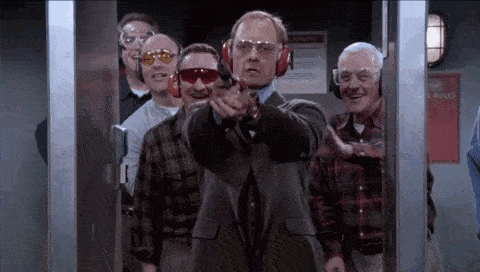 a man in a suit is shooting a gun at a group of men at a shooting range .