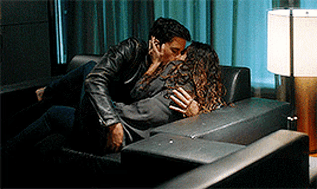 a man and woman are kissing on a couch