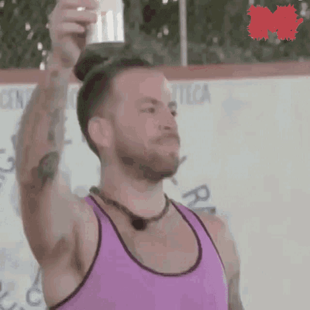 a man in a pink tank top is holding a can of soda