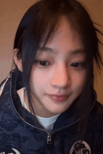 a close up of a girl 's face with a blue jacket on