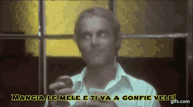 a man holding a card with the words mangia le mele e ti va a gonfie vele written above him