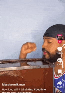 a man with a beard is drinking milk from a box