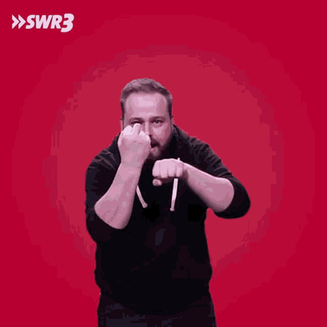 a man with a beard is giving the middle finger in front of a red background with swr3 written on it
