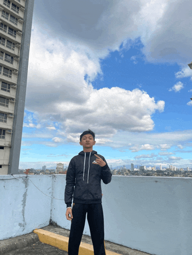 a man wearing a nike hoodie stands on a rooftop