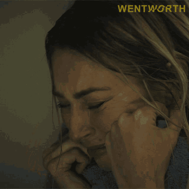 a close up of a woman covering her face with a towel with the word wentworth above her