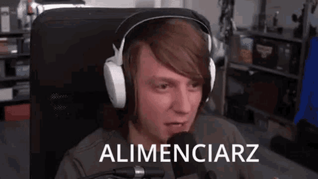a man wearing headphones is sitting in front of a microphone and talking into it .
