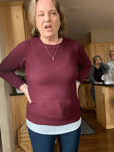 a woman wearing a maroon sweater and a cross necklace