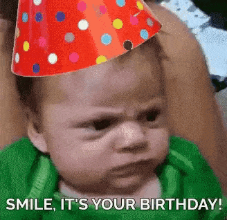 a baby wearing a party hat is making a funny face and saying `` smile , it 's your birthday ! ''