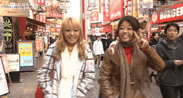 two women are walking down a street in front of a burger king
