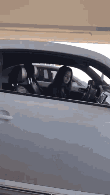a woman is sitting in a car looking out the window